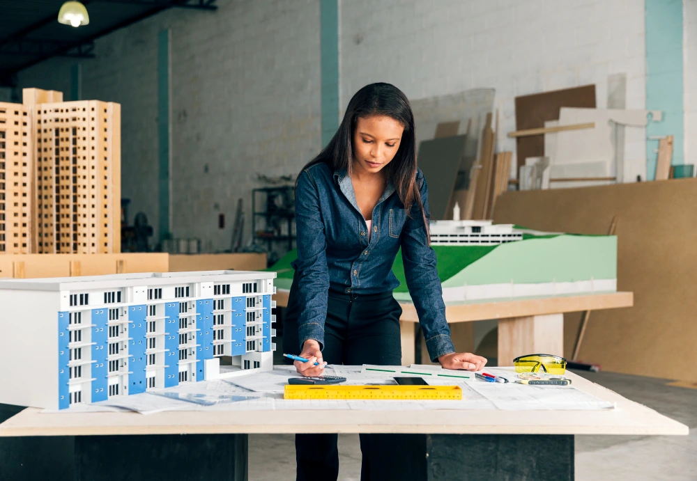 Professional woman in dark blazer examining architectural scale models of residential buildings on white table in modern design studio with materials and supplies in background. - Garage Conversion Estimator