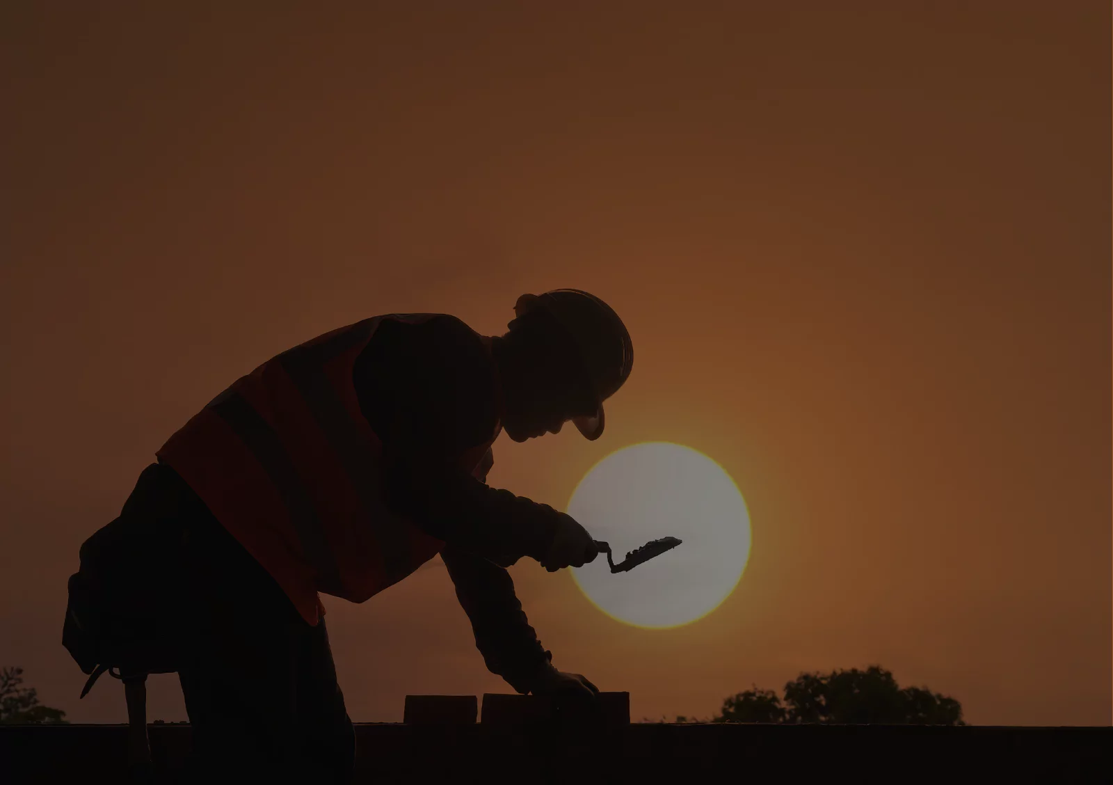 Construction worker silhouette using hammer tool at sunset on building site for labor cost calculation